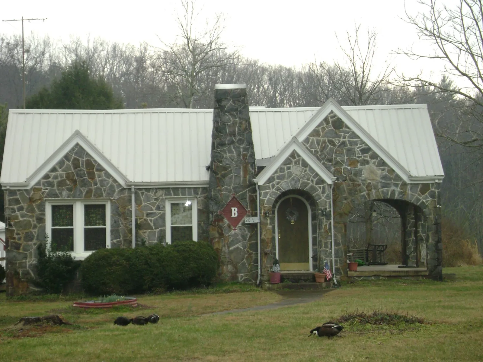 White metal roof on a stone cottage with steep gables in Elk River