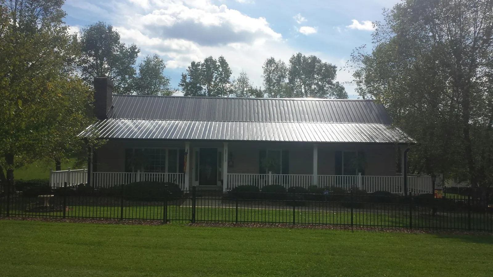 Gray metal roof on a brick ranch with a full width front porch — Gutter Guard Installation work by our crew in Elk River