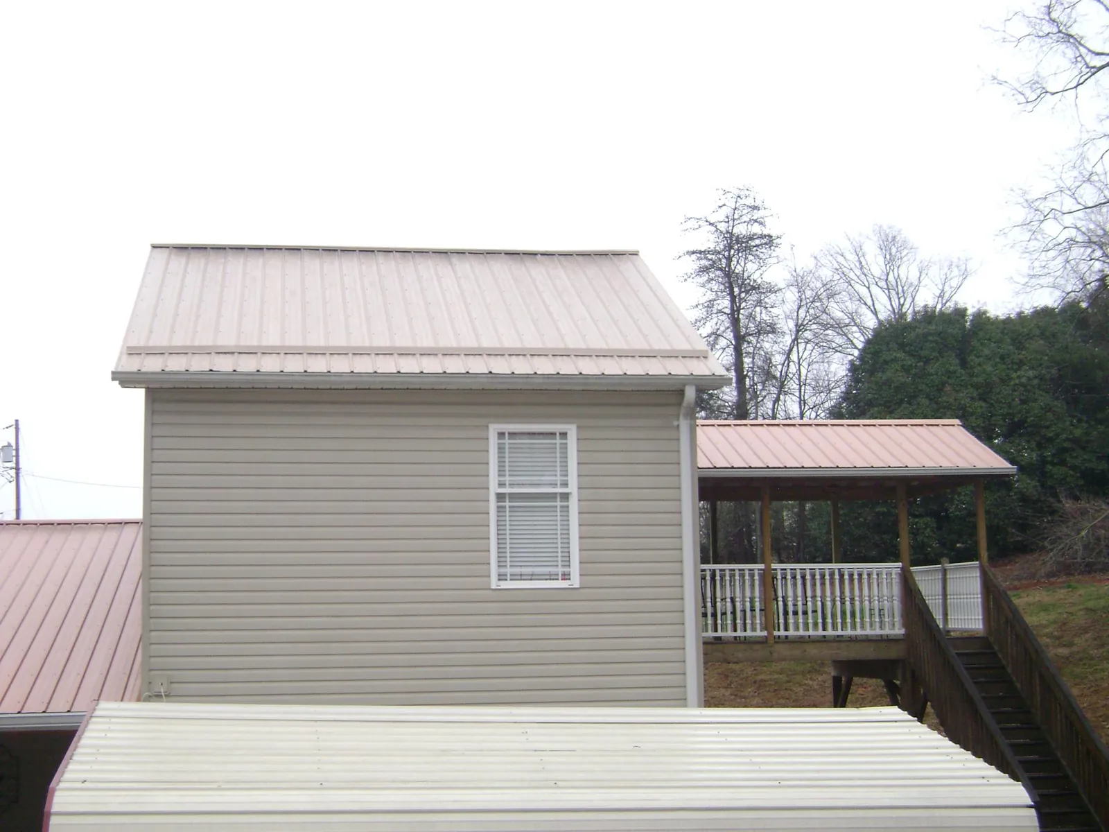 Tan metal roofs on a two story addition and attached porch, from a Roof Replacement job in Elk River